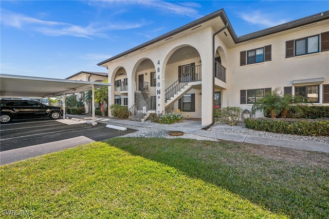 view of front of house featuring stucco siding, covered parking, and a front lawn