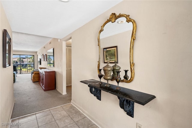 hall featuring light tile patterned flooring, light colored carpet, and baseboards