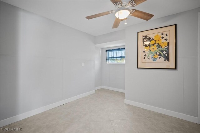 empty room featuring light tile patterned flooring, baseboards, and ceiling fan