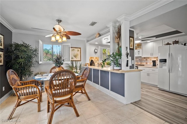 dining space with crown molding, light tile patterned floors, a ceiling fan, and visible vents