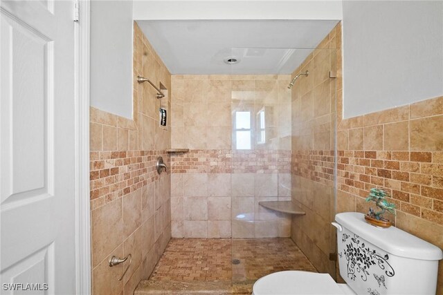 bathroom with toilet, tile walls, and a tile shower