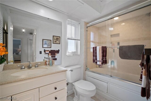 bathroom with vanity, toilet, and bath / shower combo with glass door