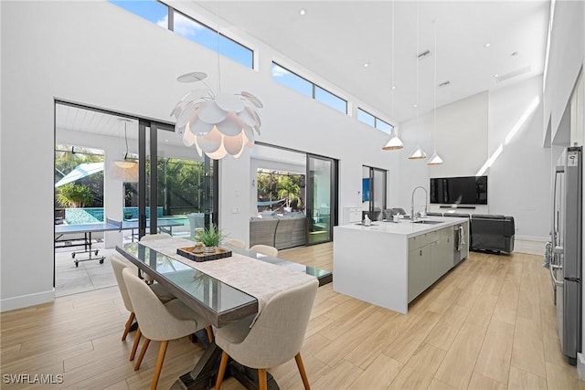 dining room with a high ceiling, baseboards, and light wood finished floors