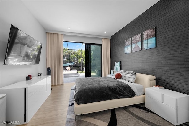 bedroom featuring access to exterior, light wood finished floors, brick wall, and an accent wall