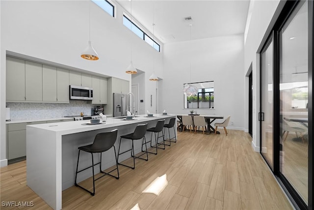 kitchen with a sink, appliances with stainless steel finishes, light wood-style flooring, and gray cabinets