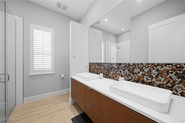 full bath featuring a shower stall, baseboards, decorative backsplash, wood finished floors, and a sink