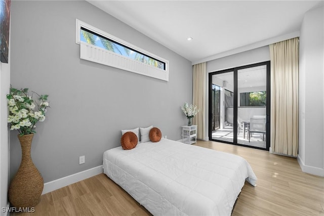 bedroom with access to exterior, light wood-style flooring, and baseboards