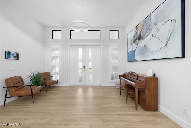 entryway with french doors, baseboards, and light wood-style flooring