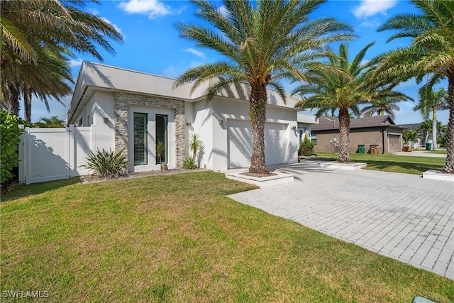 view of front facade featuring stucco siding, a front lawn, decorative driveway, fence, and a garage