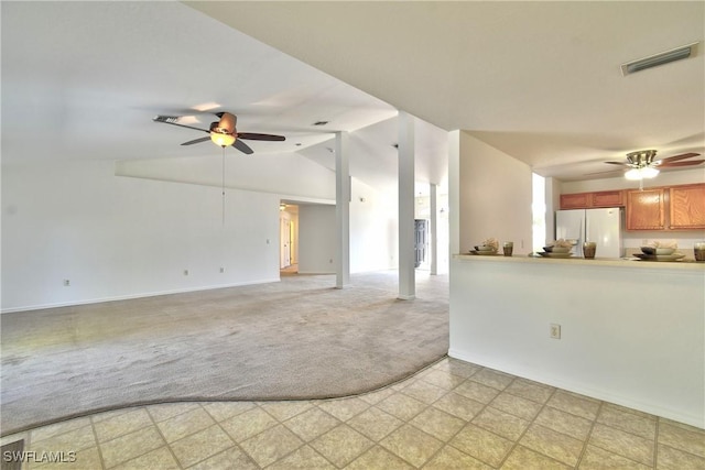 unfurnished living room with vaulted ceiling, light colored carpet, visible vents, and ceiling fan