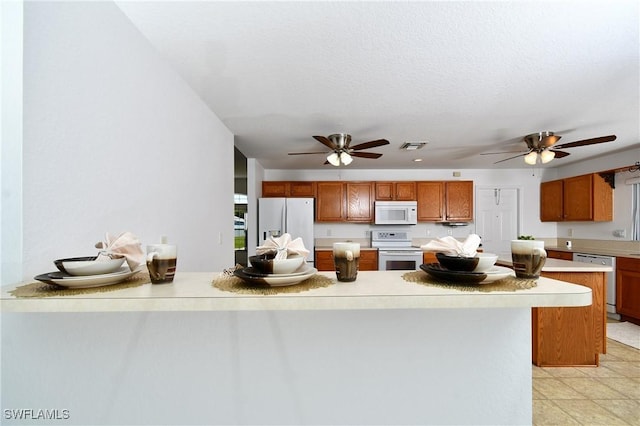 kitchen featuring white appliances, light countertops, brown cabinets, and ceiling fan