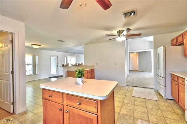 kitchen featuring a ceiling fan, visible vents, freestanding refrigerator, light countertops, and open floor plan