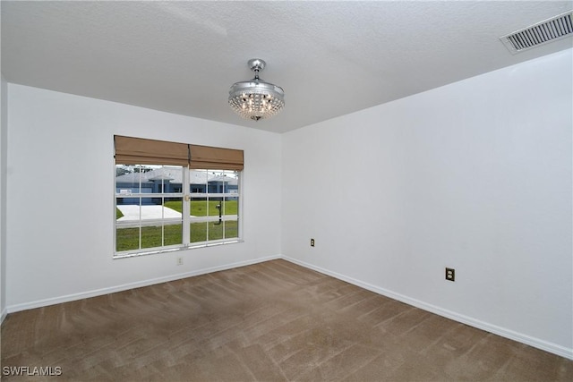 unfurnished room featuring visible vents, baseboards, a chandelier, carpet floors, and a textured ceiling