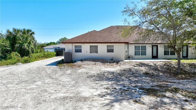 rear view of house with stucco siding and roof with shingles