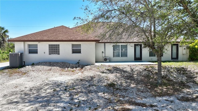 view of front of home with a patio area, central AC, stucco siding, and a shingled roof