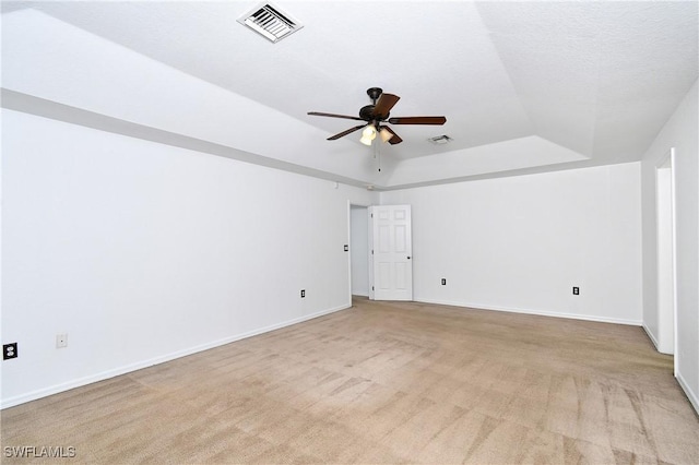 unfurnished room with visible vents, light carpet, a ceiling fan, baseboards, and a raised ceiling