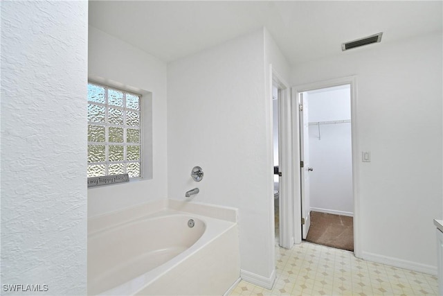 full bathroom with tile patterned floors, visible vents, a garden tub, baseboards, and a spacious closet