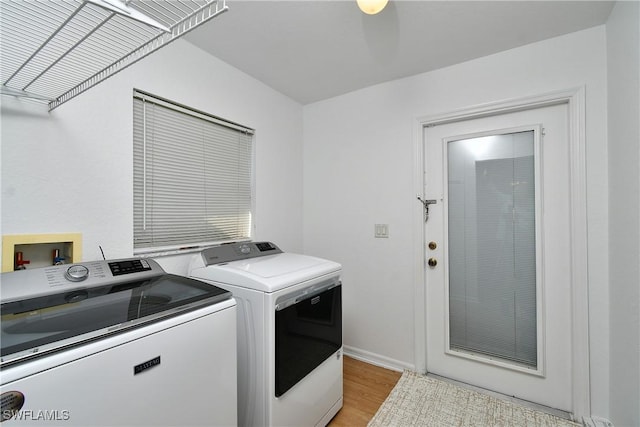 clothes washing area with light wood-type flooring, baseboards, laundry area, and washer and clothes dryer