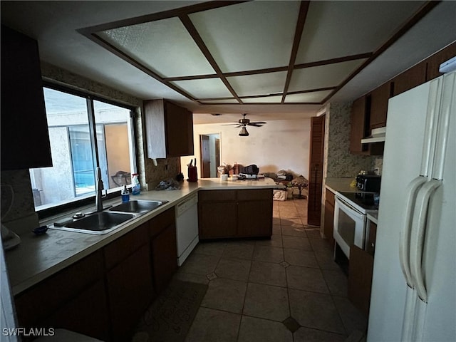 kitchen with a sink, under cabinet range hood, open floor plan, white appliances, and a peninsula