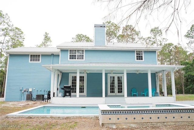 rear view of house with an outdoor pool, french doors, a chimney, and ceiling fan