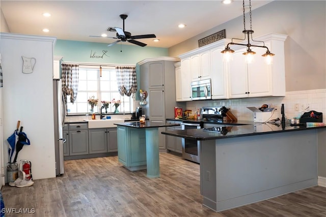 kitchen with decorative backsplash, appliances with stainless steel finishes, light wood-type flooring, and a peninsula