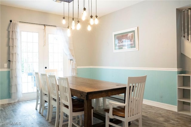 dining space featuring a wainscoted wall, baseboards, and wood finished floors