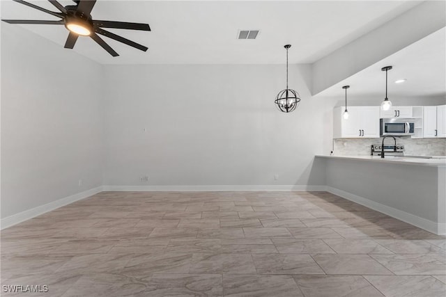 kitchen with visible vents, decorative backsplash, light countertops, white cabinets, and stainless steel microwave