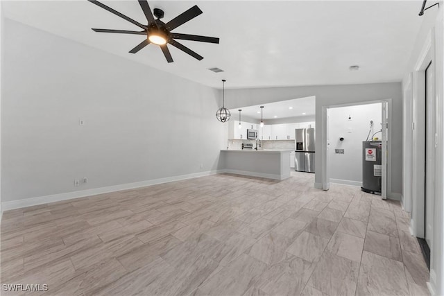 unfurnished living room featuring visible vents, ceiling fan with notable chandelier, water heater, baseboards, and lofted ceiling