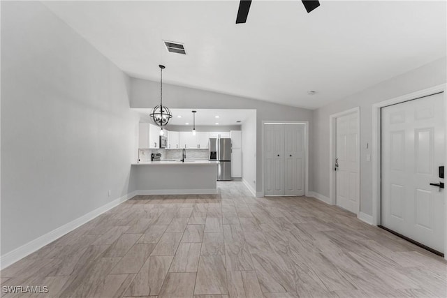 unfurnished living room featuring baseboards, visible vents, a sink, vaulted ceiling, and light wood-type flooring