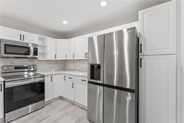 kitchen with open shelves, light countertops, appliances with stainless steel finishes, white cabinetry, and backsplash