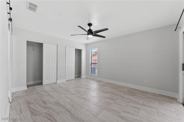 unfurnished bedroom with visible vents, ceiling fan, baseboards, and multiple closets