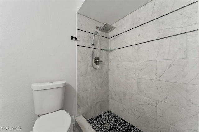 bathroom featuring tiled shower and toilet