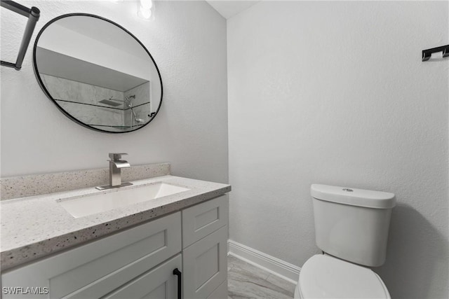 bathroom featuring toilet, vanity, and baseboards