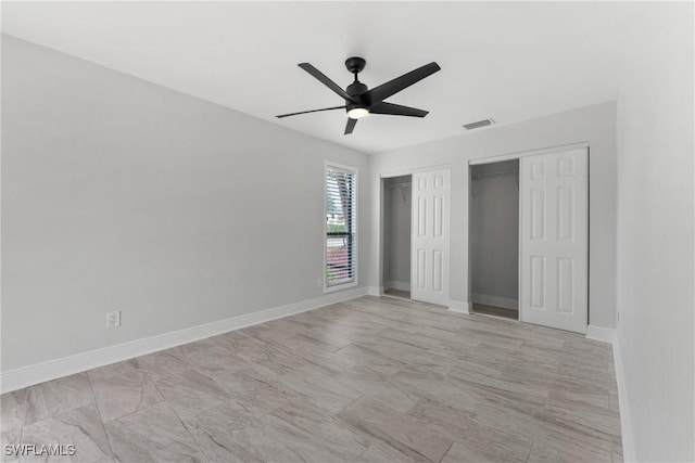 unfurnished bedroom featuring visible vents, baseboards, two closets, and a ceiling fan