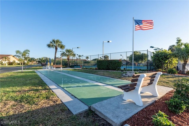 surrounding community featuring shuffleboard, a lawn, and fence