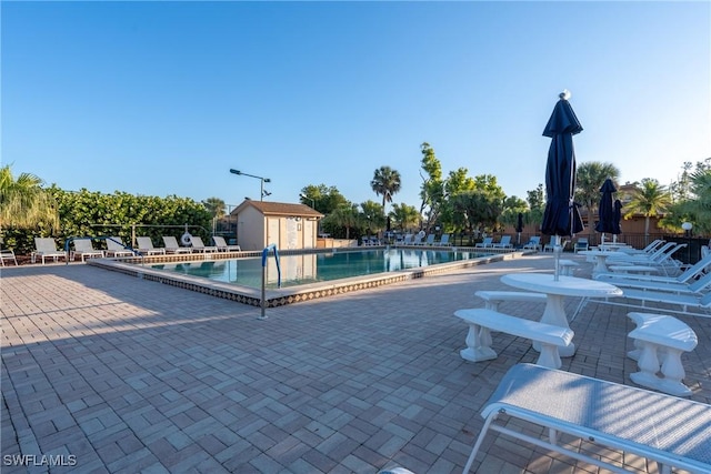 pool featuring a storage shed, an outdoor structure, a patio area, and fence