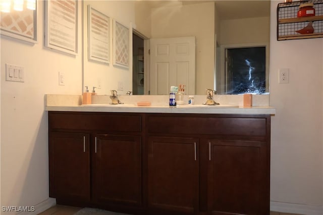 bathroom with double vanity, baseboards, and a sink