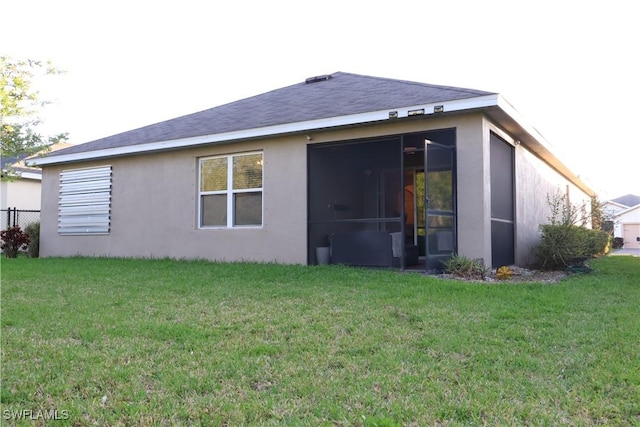 back of property featuring a yard, a sunroom, and stucco siding