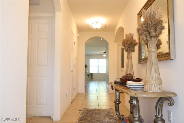 corridor with light tile patterned flooring, visible vents, arched walkways, and baseboards