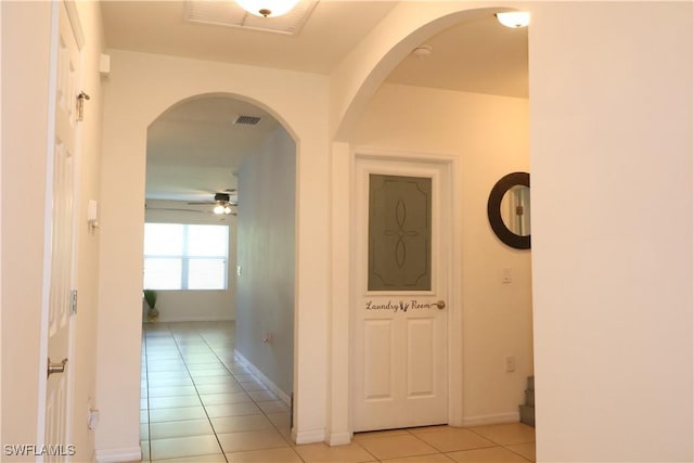 hallway with light tile patterned floors, visible vents, and baseboards