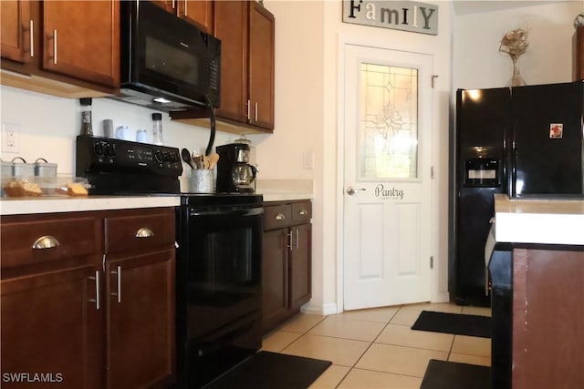 kitchen with black appliances, light tile patterned flooring, and light countertops