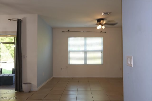 unfurnished room with light tile patterned floors, a ceiling fan, visible vents, and baseboards