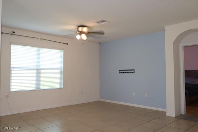 spare room with baseboards, a ceiling fan, visible vents, and arched walkways