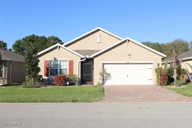 ranch-style home with stucco siding, an attached garage, decorative driveway, and a front yard