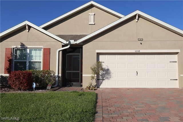 single story home featuring stucco siding, decorative driveway, and a garage