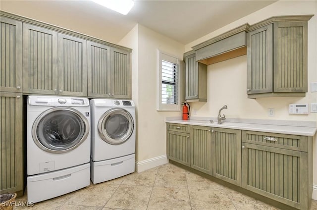 washroom with cabinet space, washing machine and dryer, baseboards, and a sink