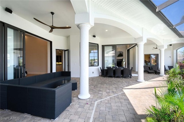 view of patio / terrace with glass enclosure, an outdoor hangout area, and a ceiling fan