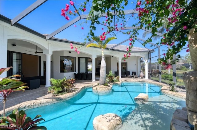 pool with glass enclosure, a patio area, and ceiling fan