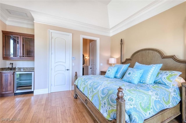 bedroom with crown molding, wine cooler, indoor wet bar, light wood-style floors, and a sink