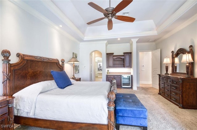 bedroom featuring a raised ceiling, wine cooler, crown molding, and light carpet